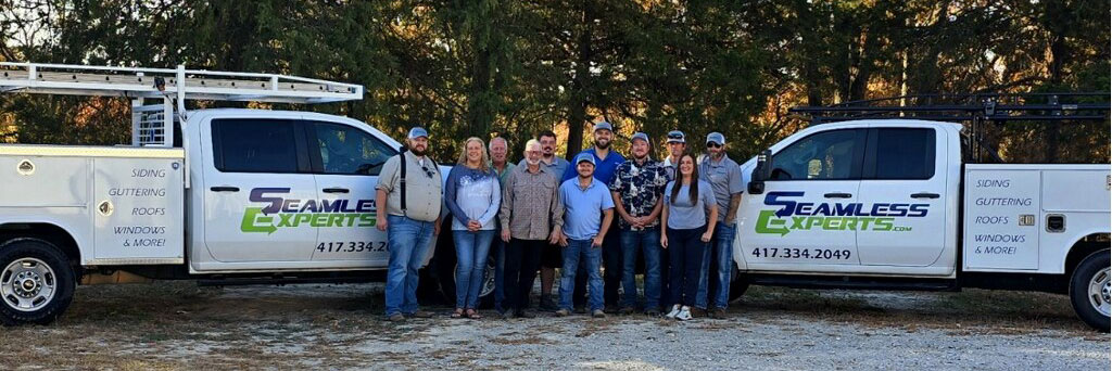 team members pose in front of work trucks at Seamless Experts residential and commercial exterior remodeling Ozarks Missouri