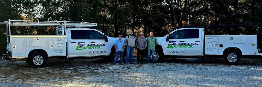 a few team members pose in front of two work trucks at Seamless Experts residential and commercial exterior remodeling Ozarks Missouri