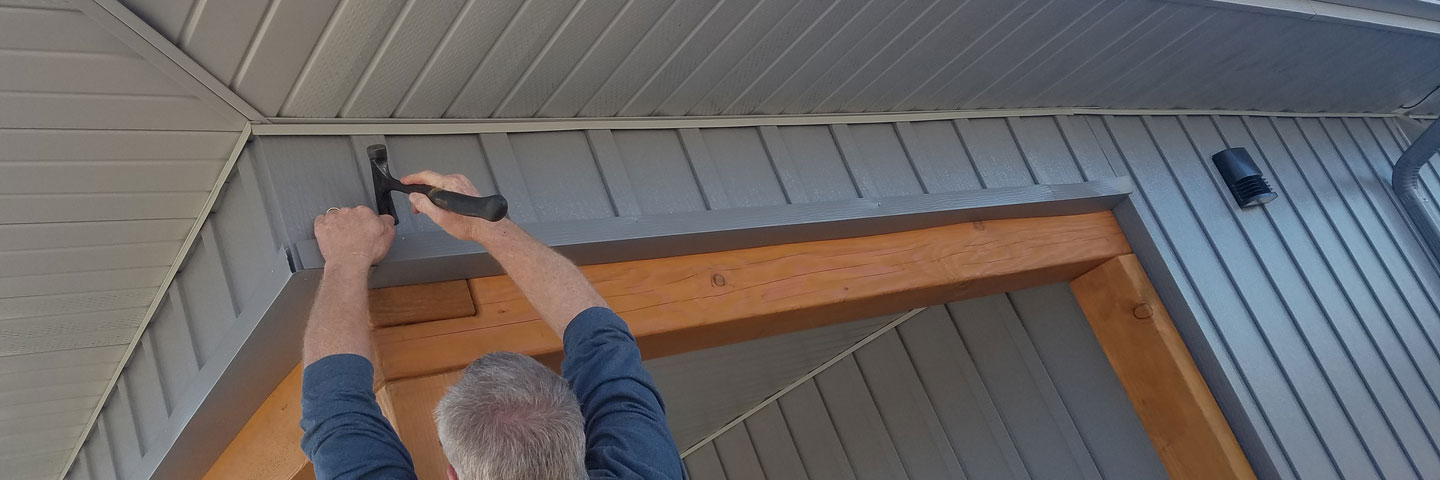 carpenter installing soffit at a building Seamless Experts residential and commercial exterior remodeling Ozarks Missouri