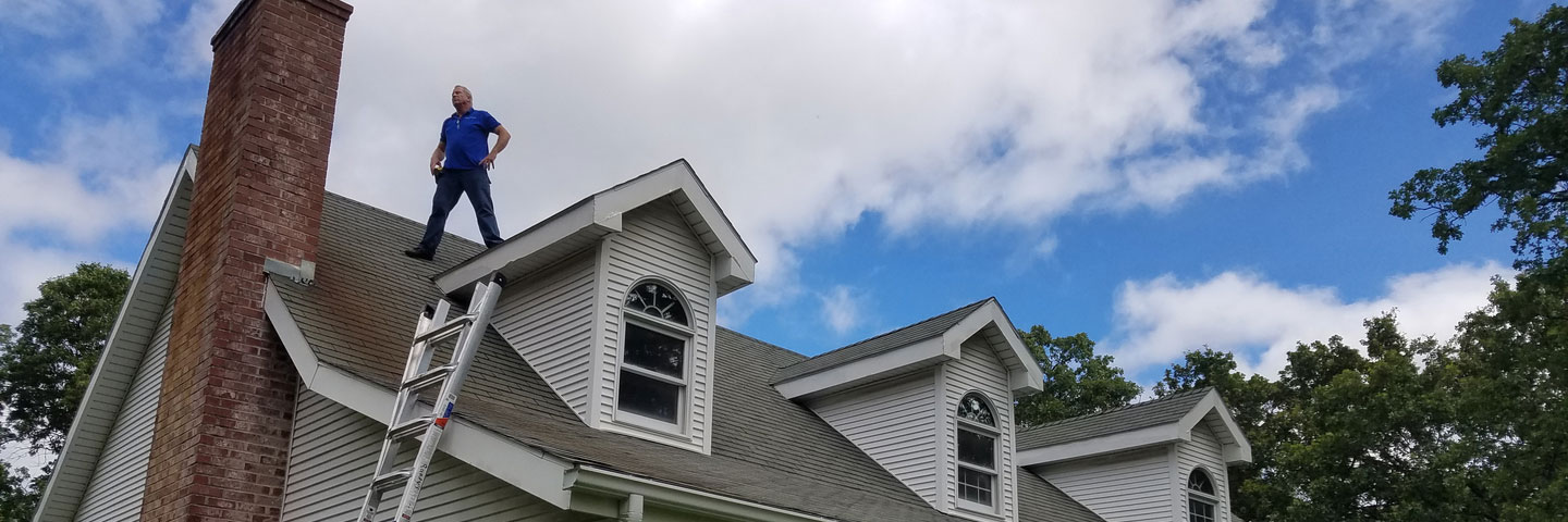 man standing on roof Seamless Experts residential and commercial exterior remodeling Ozarks Missouri